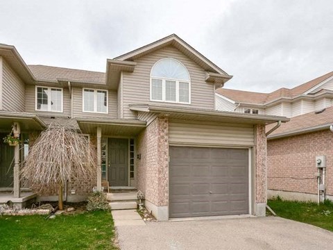 A two-story house with a garage door and a tree in front.