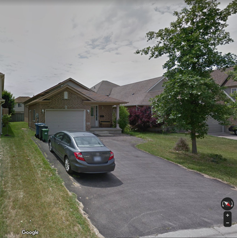 A grey car is parked in front of a house.