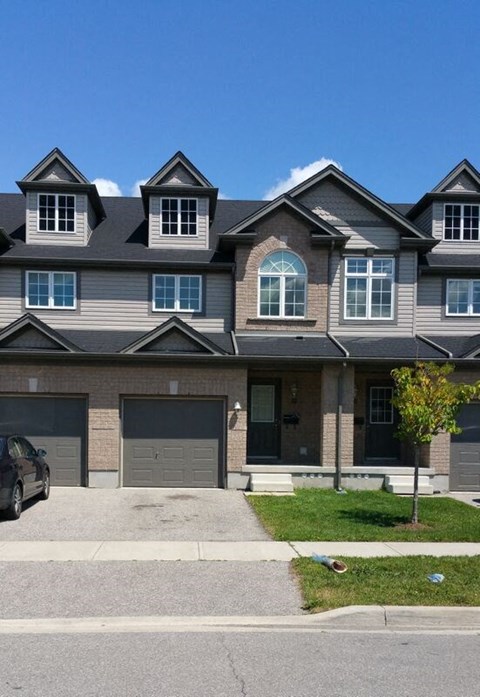 A grey house with a black car parked in front.