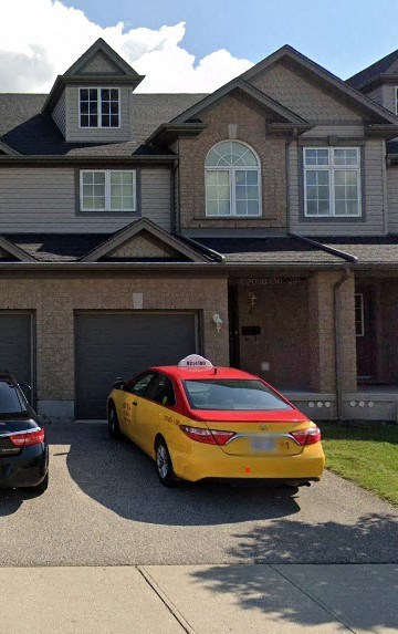 A yellow taxi is parked in front of a house.