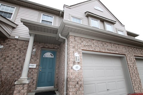 a brick house with a blue door and two garage doors