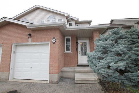A house with a white garage door and a number 55 on the wall.