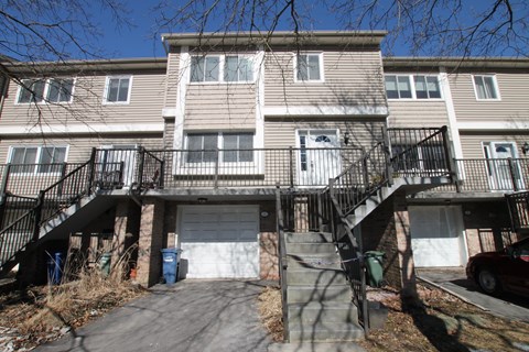 the front of an apartment building with stairs and a garage