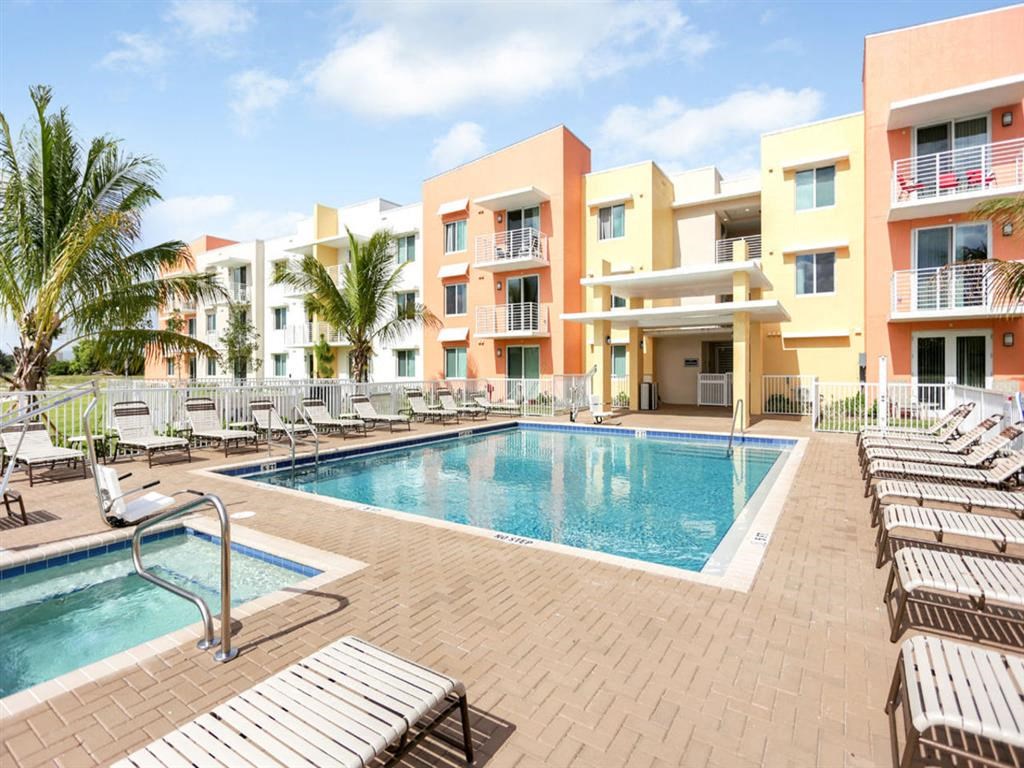 a swimming pool with lounge chairs in front of an apartment building