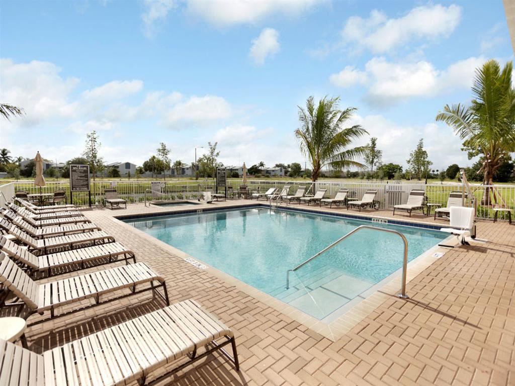 a swimming pool with wooden chairs and chairs around it