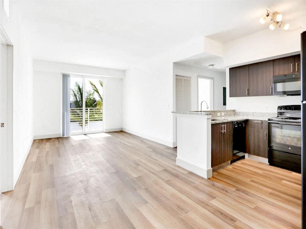 the living room and kitchen of an apartment with wood flooring