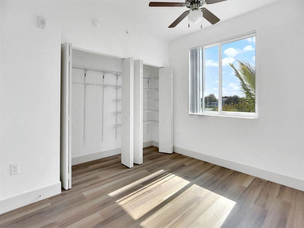 an empty living room with a window and a ceiling fan