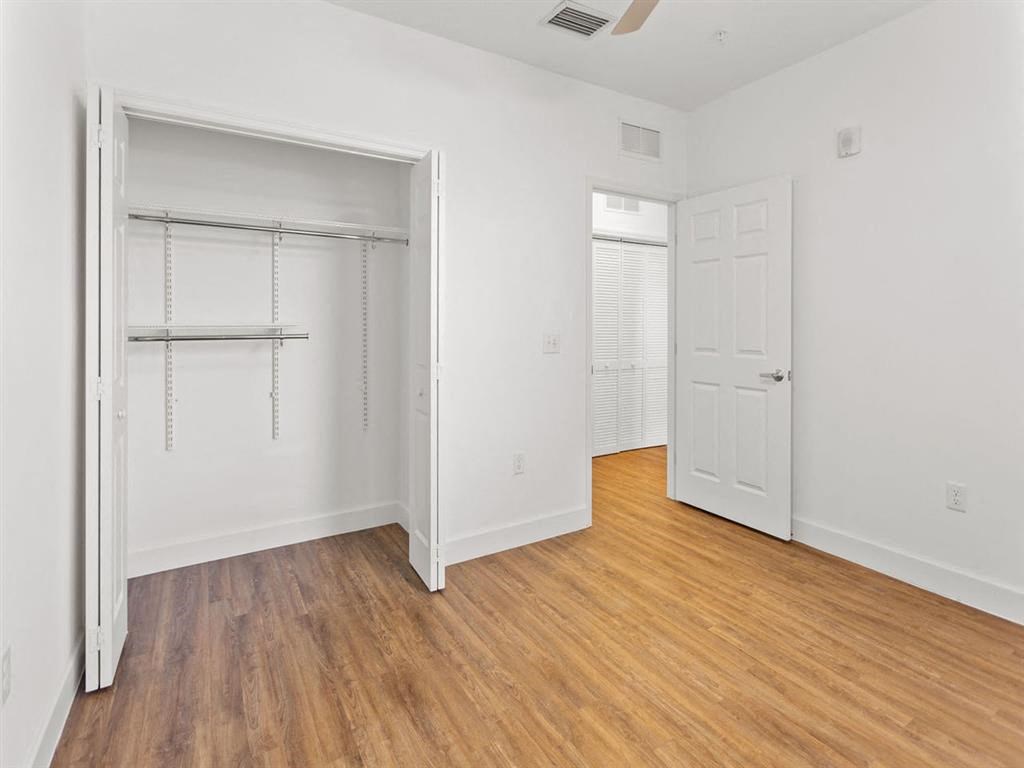 an empty bedroom with wood floors and a closet