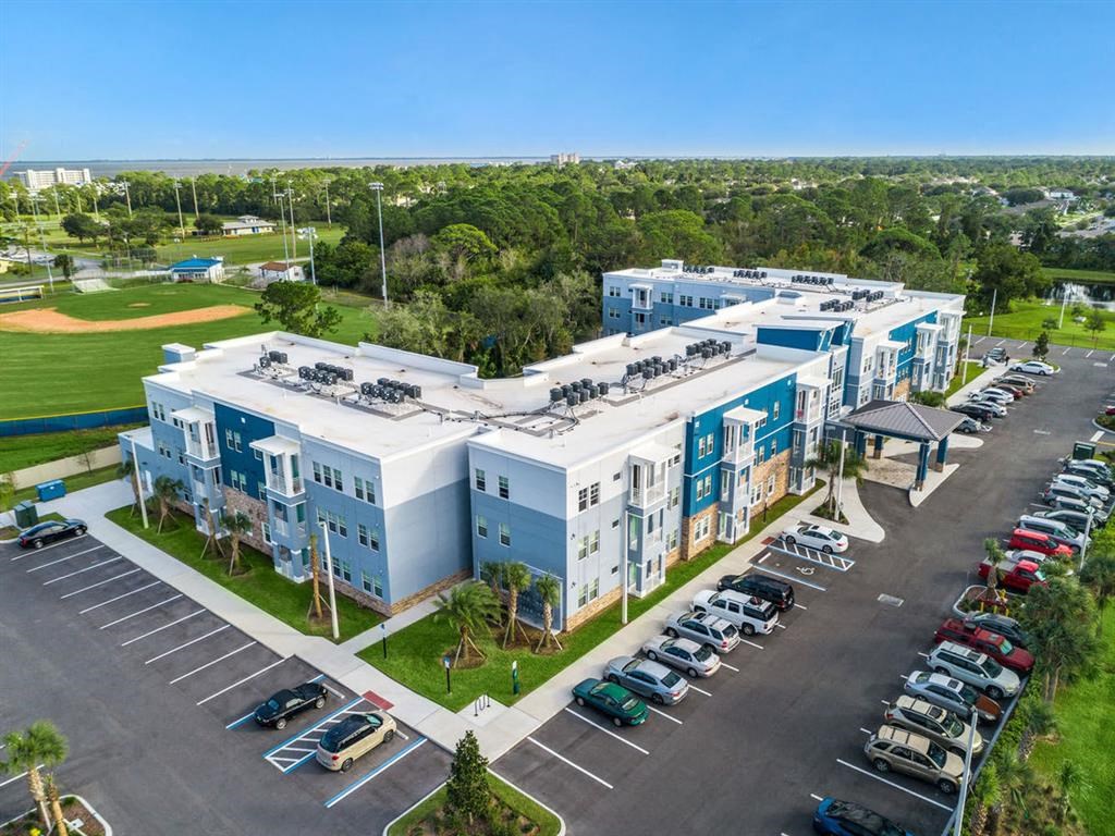 an aerial view of a building with cars parked in a parking lot