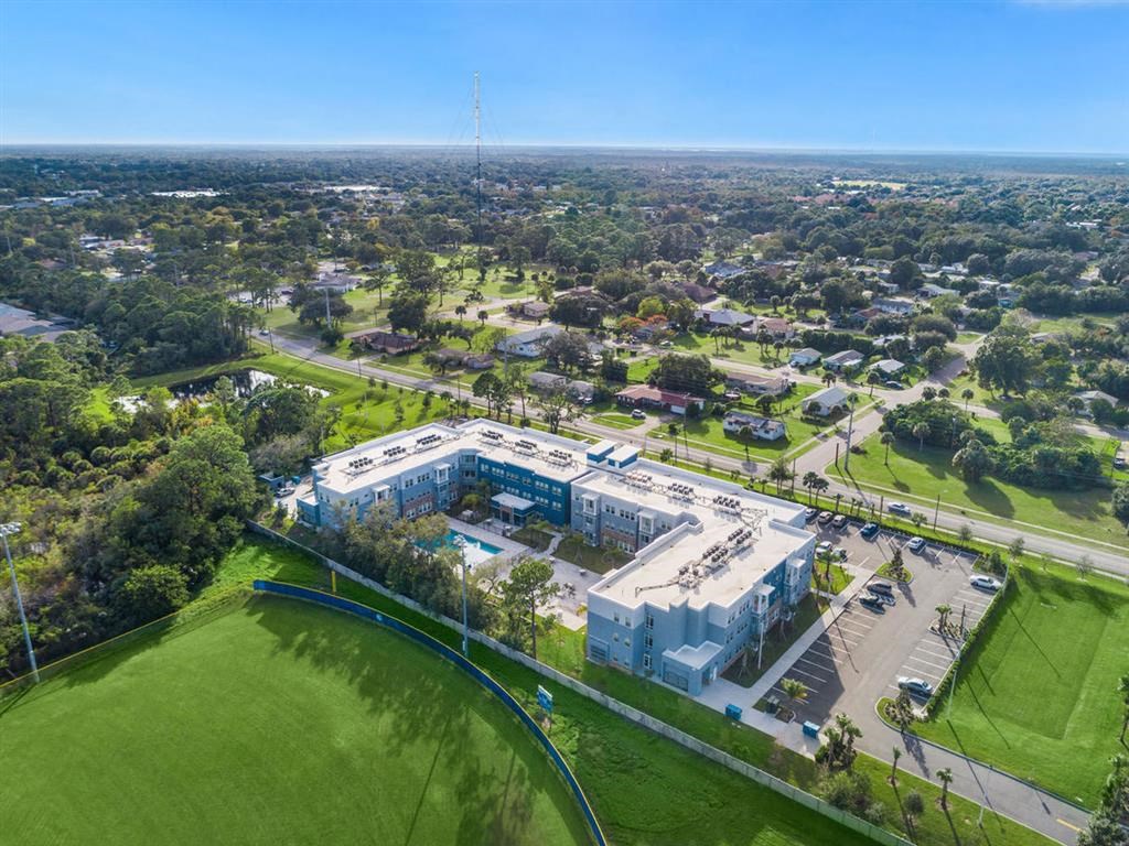 an aerial view of a building next to a green field