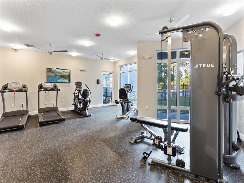 a gym with exercise equipment on the floor and a window