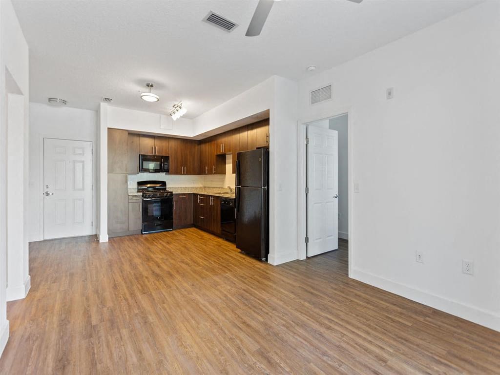 an empty living room and kitchen with a wood floor