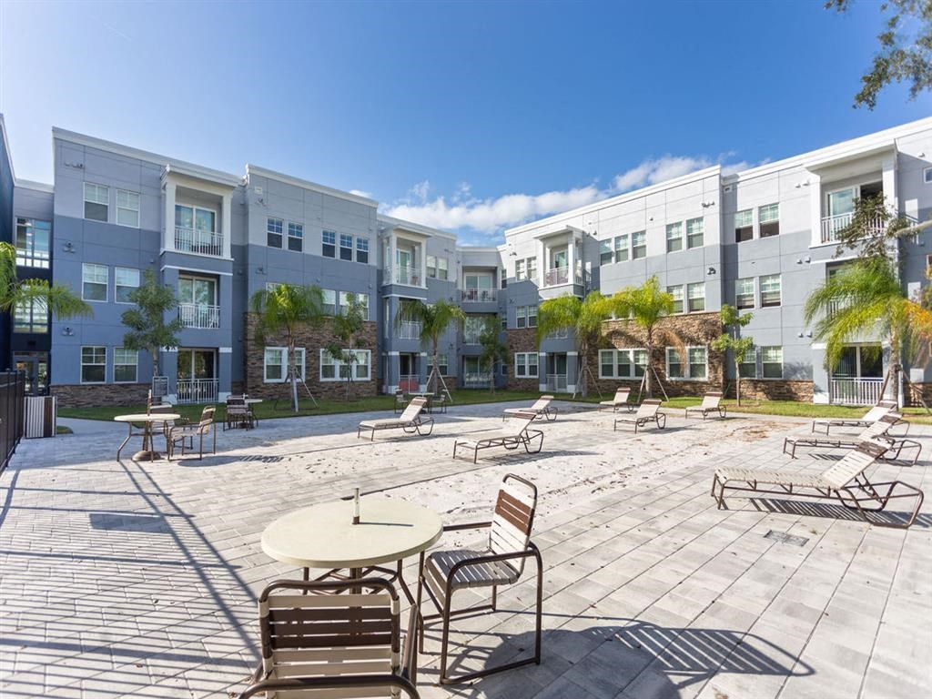 a patio with tables and chairs in front of an apartment building