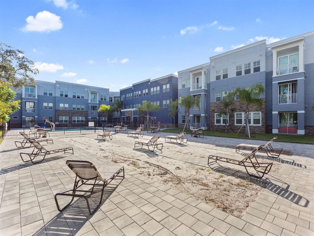 a large patio with chairs and tables in front of an apartment building
