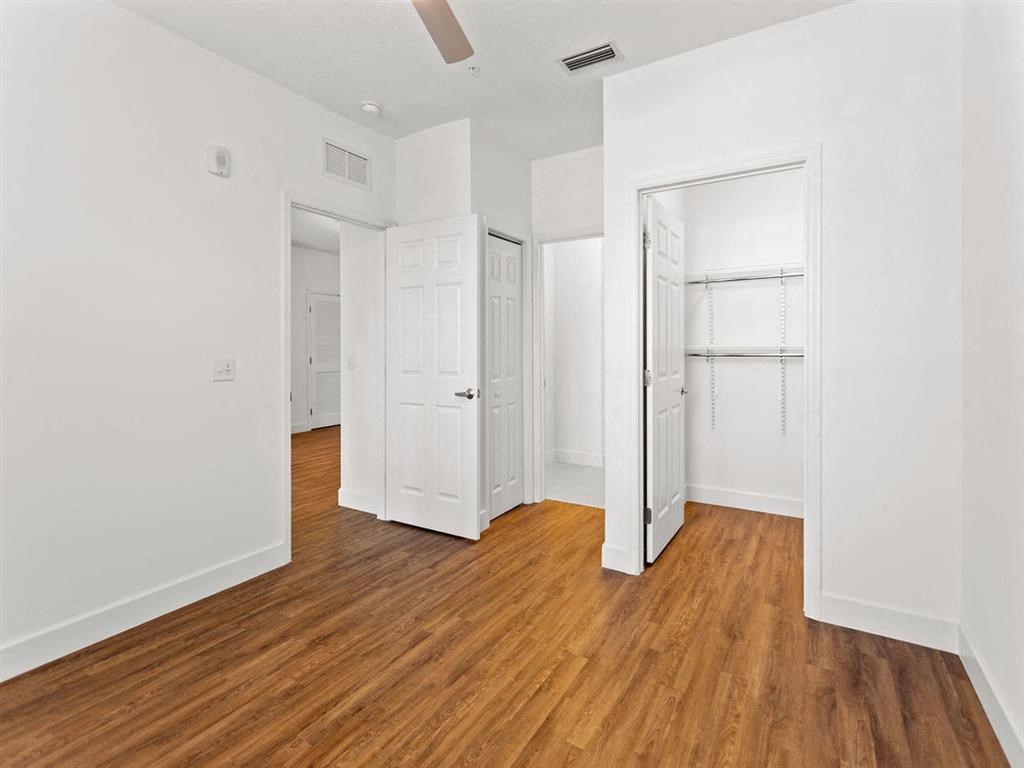 a bedroom with white walls and wood floors and a closet