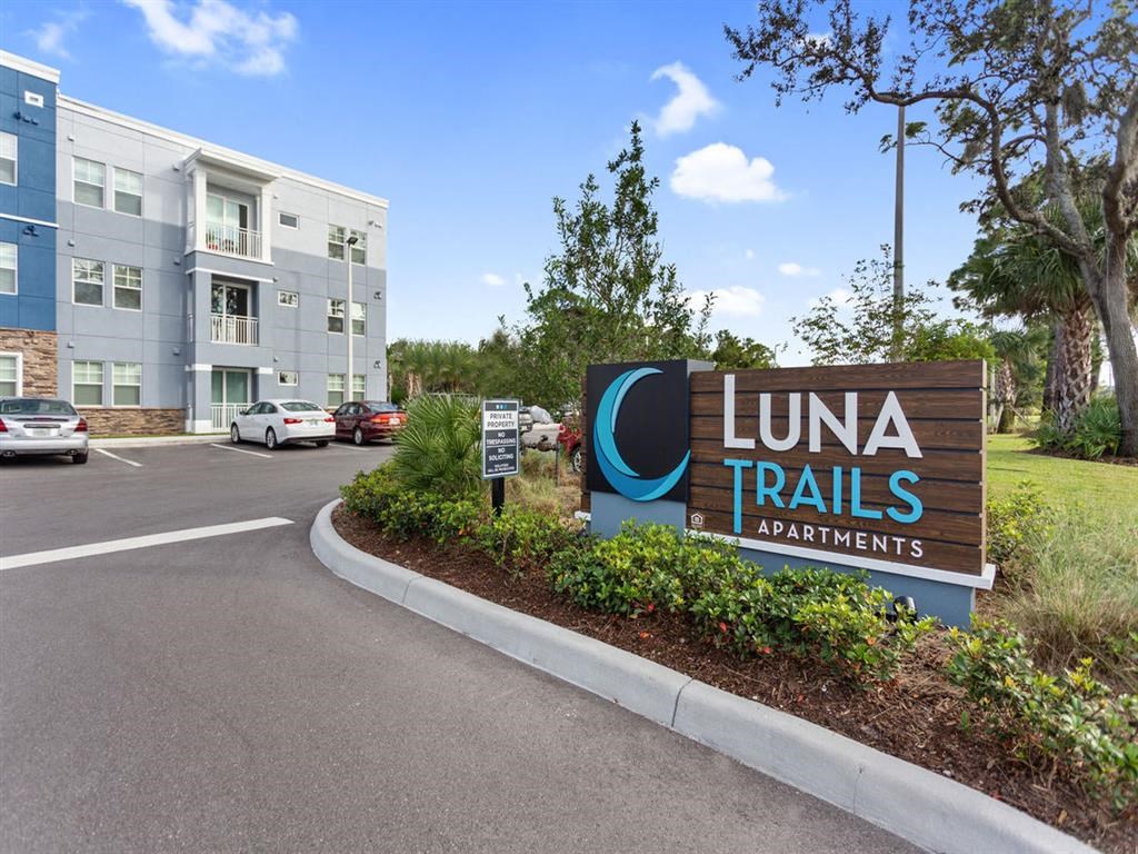 a sign for luna trails apartments in front of a parking lot