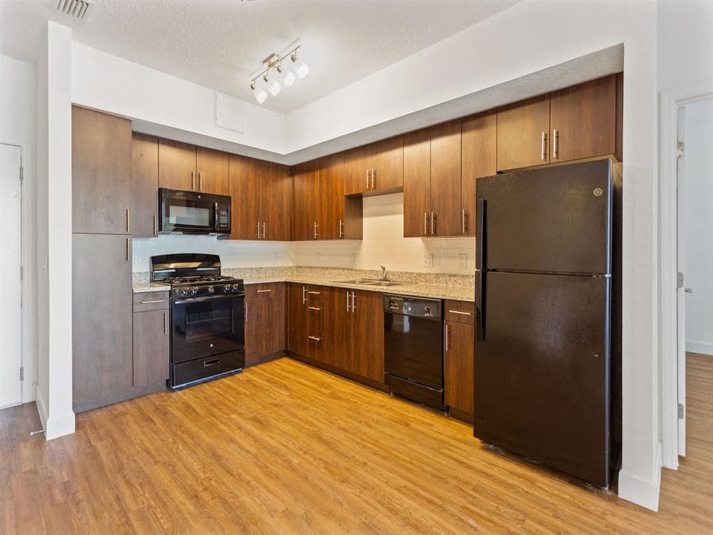 a large kitchen with black appliances and wood floors