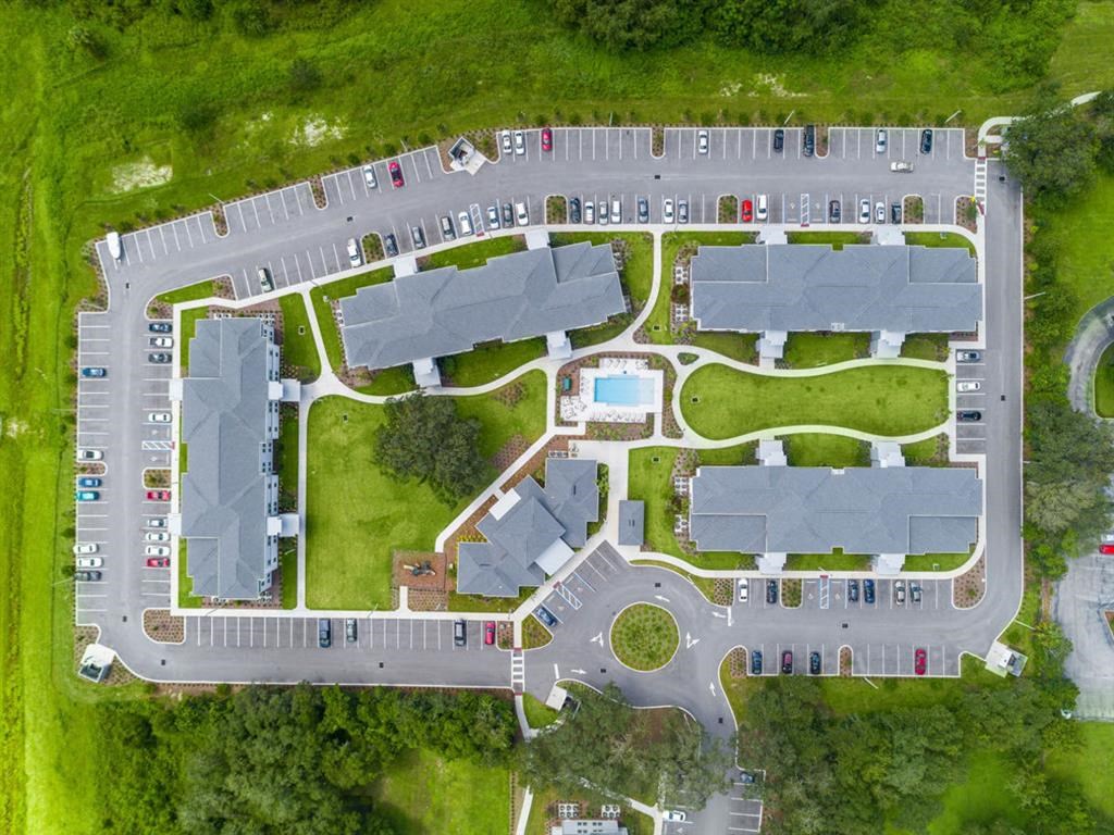 an overhead view of a parking lot with houses and grass