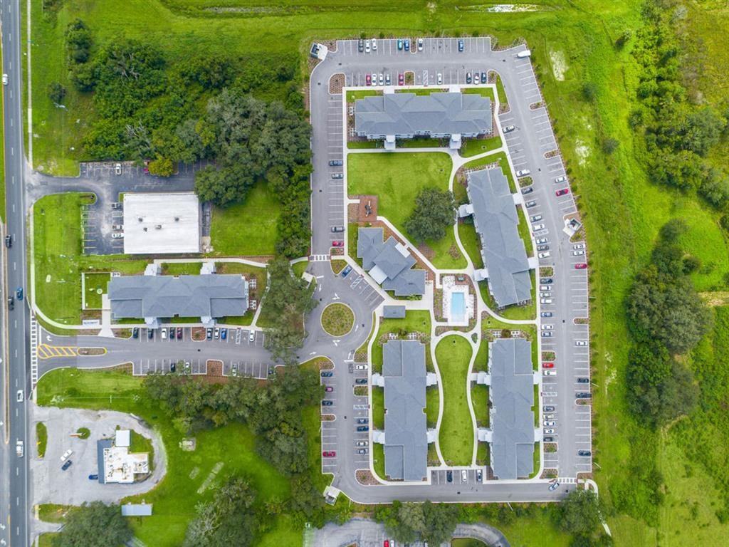 a birdseye view of a parking lot and a street with houses and trees