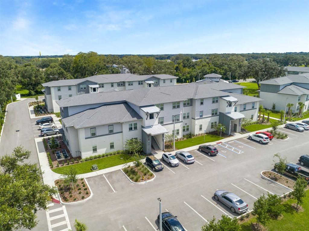 an aerial view of an apartment complex with parking lot and cars