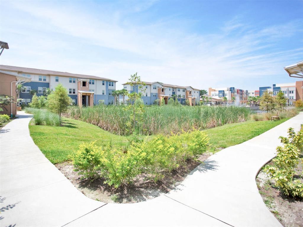 a park with grass and bushes in front of some apartments