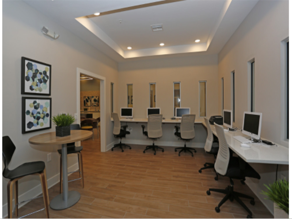 a room with a long table with computers and chairs