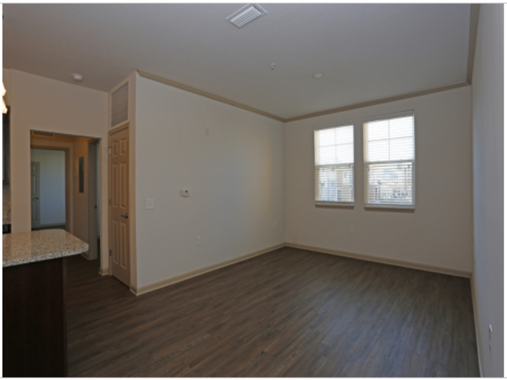 an empty living room with wood floors and white walls