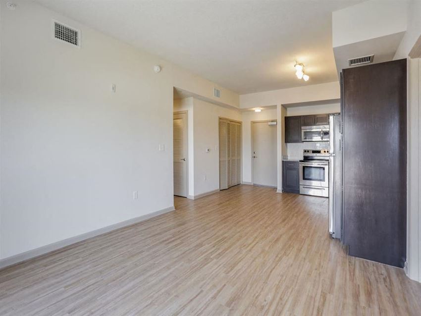 an empty living room and kitchen with a wood floor