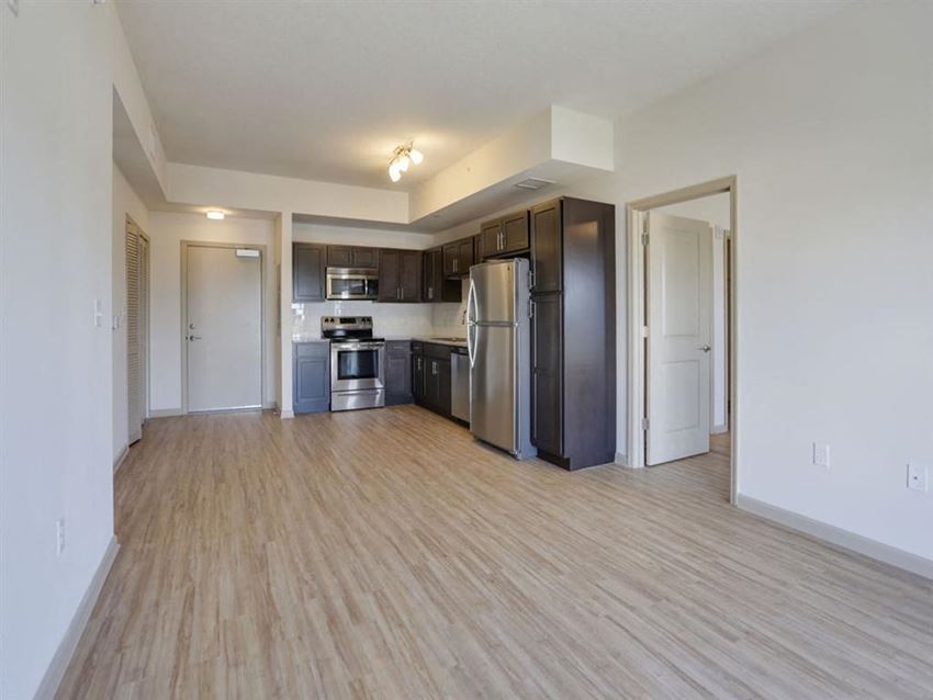 an empty living room and kitchen with stainless steel appliances