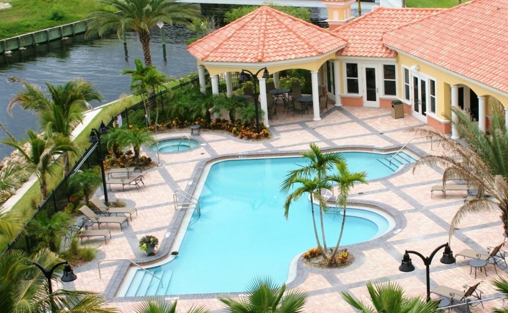 a large swimming pool in front of a house with palm trees
