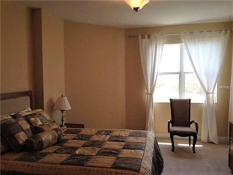 a bedroom with a bed and a chair and a window