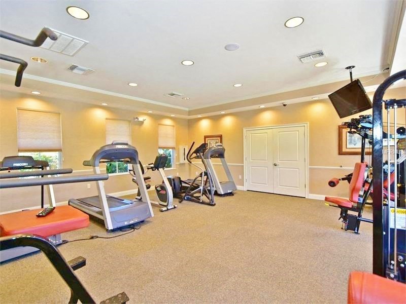 the gym has plenty of exercise equipment and a tv