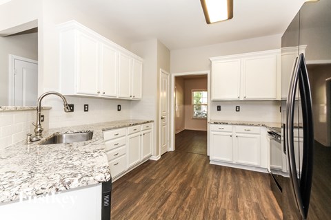 A kitchen with white cabinets and a marble countertop.