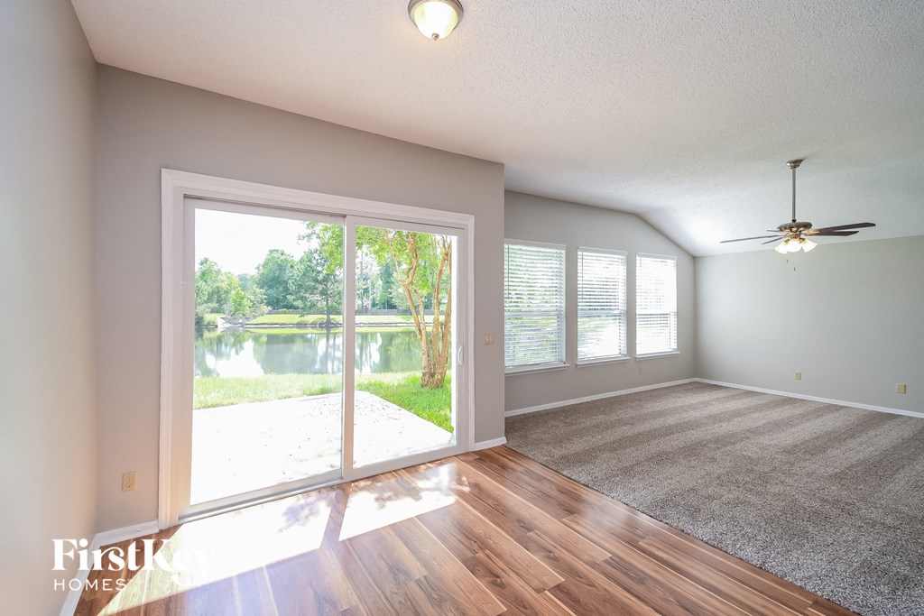 an empty living room with a large window overlooking a lake