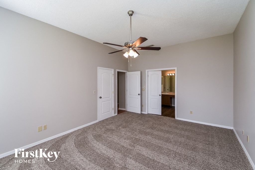 a spacious living room with carpet and a ceiling fan