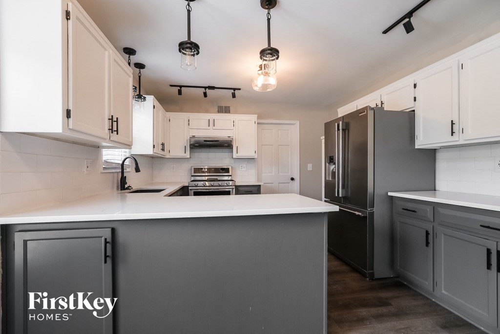 a gray and white kitchen with white countertops and stainless steel appliances