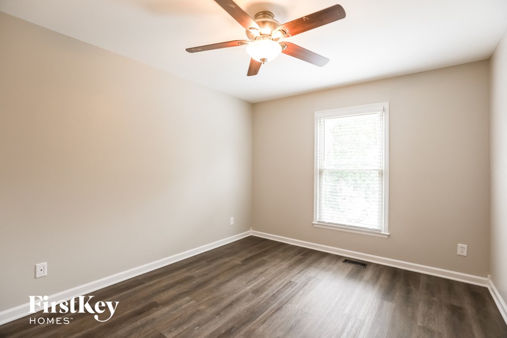 a bedroom with wood floors and a ceiling fan