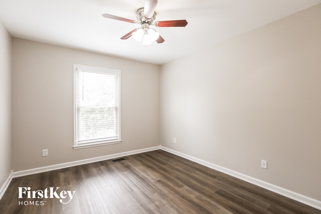 a bedroom with wood flooring and a ceiling fan