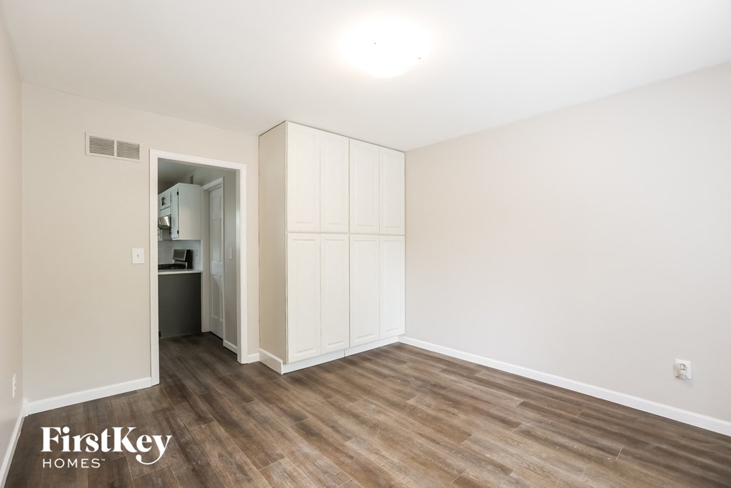 a bedroom with white walls and wood flooring and a closet