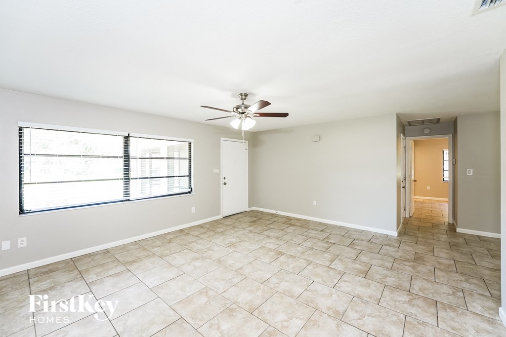 A spacious room with a ceiling fan and tiled floor.