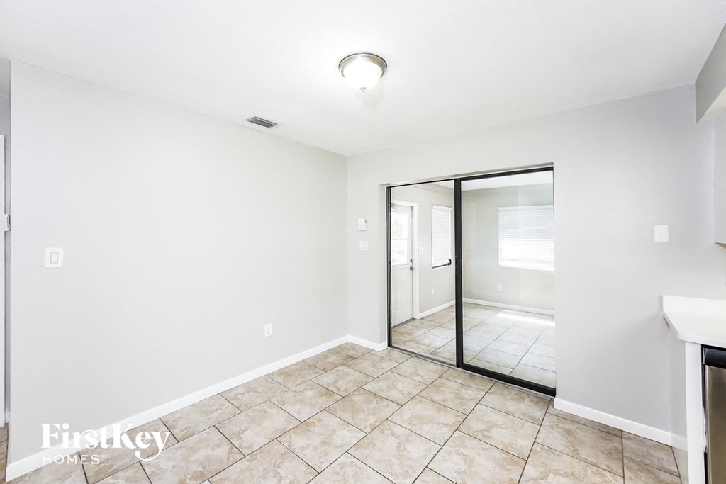 A room with a tiled floor and a glass door leading to another room.