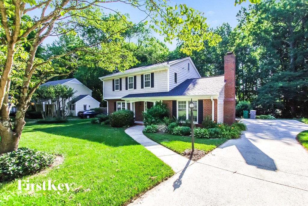 a white house with a lawn and a brick chimney