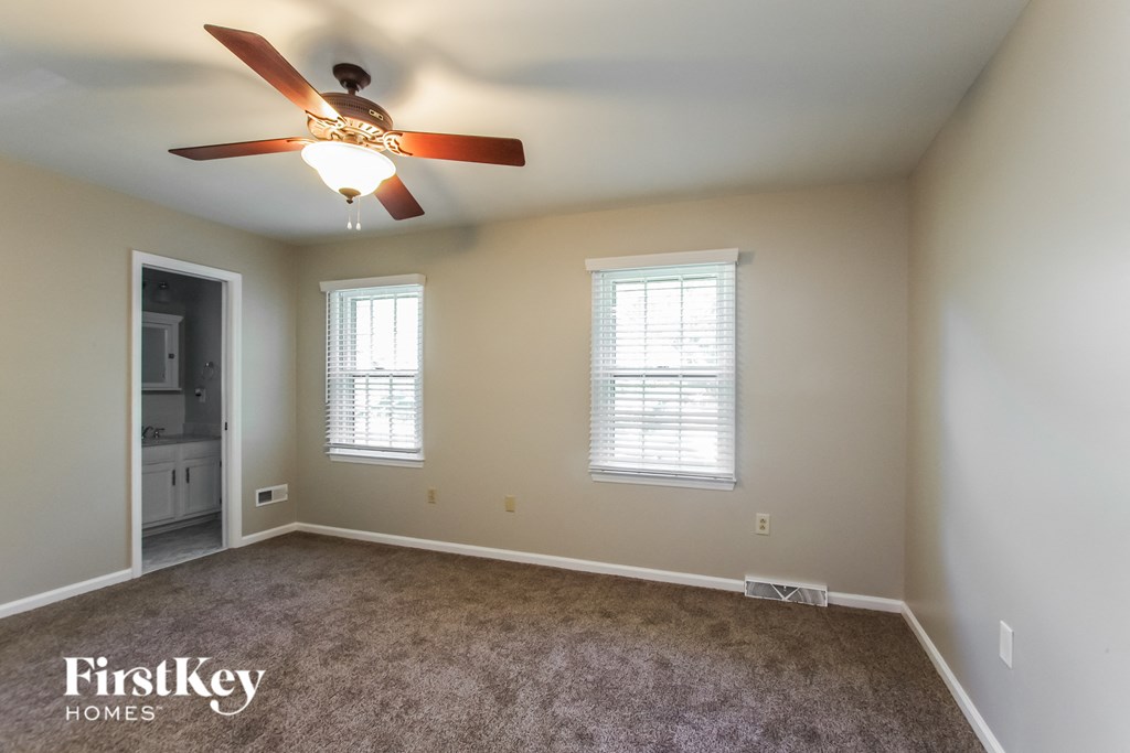 an empty room with a ceiling fan and two windows