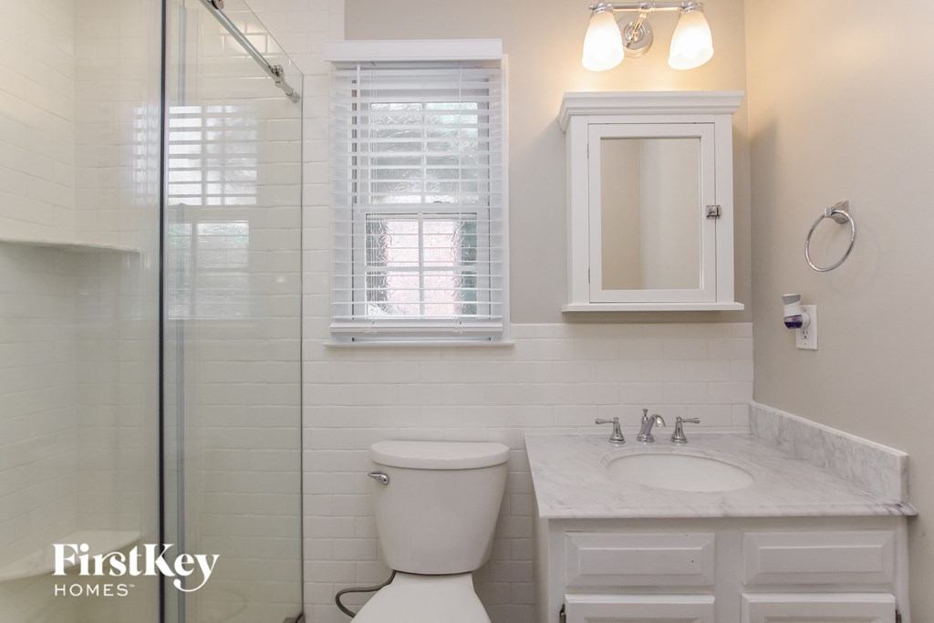 a white bathroom with a toilet and a sink and a shower