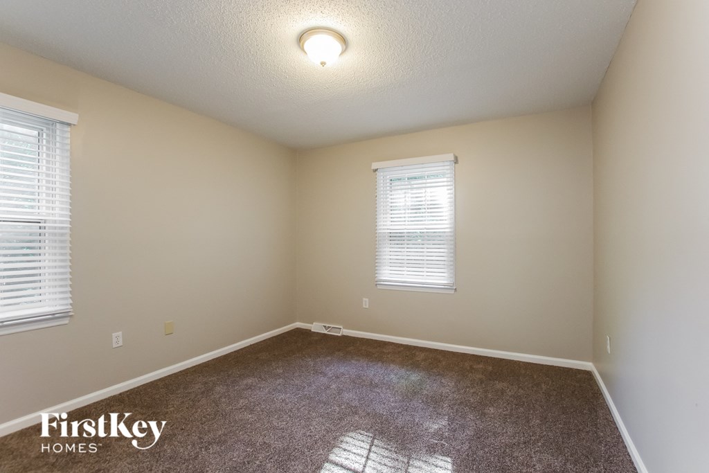 the upstairs bedroom with carpeted flooring and two windows