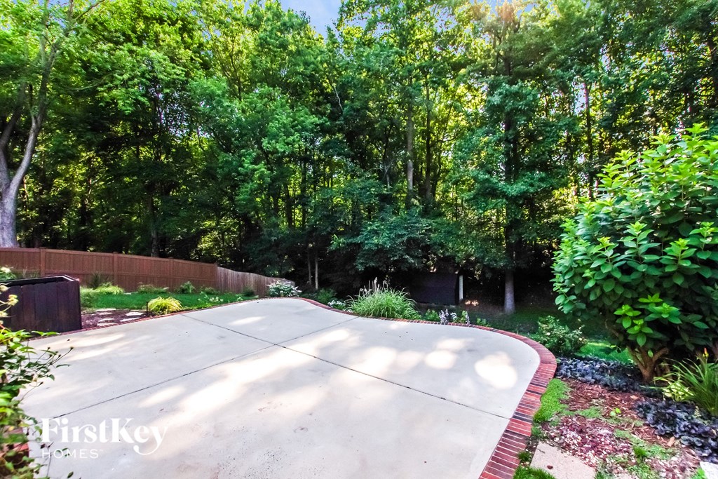 a driveway leading into a garden with trees and bushes