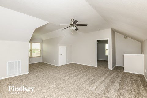 a spacious living room with carpet and a ceiling fan
