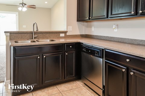 A kitchen with dark brown cabinets and a stainless steel dishwasher.