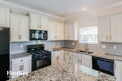 A kitchen with granite countertops and white cabinets.