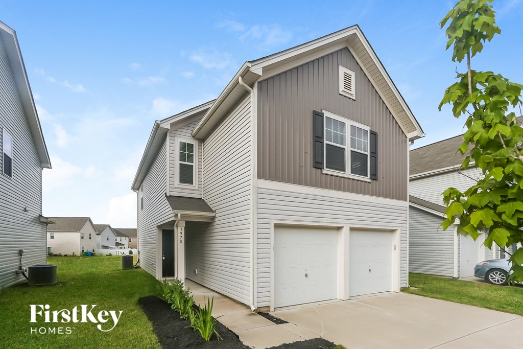 a gray house with two garage doors and a driveway